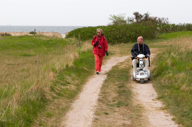Man in a wheelchair walking with his wife near the beach
